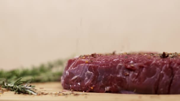 Gotas de tempero em pedaços de carne de vaca vermelha fresca crua na mesa — Vídeo de Stock