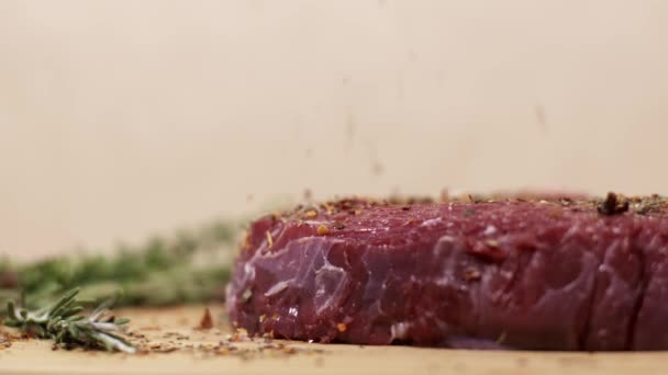 Especiarias que caem em pedaços de bife cru de carne vermelha fresca na mesa — Vídeo de Stock