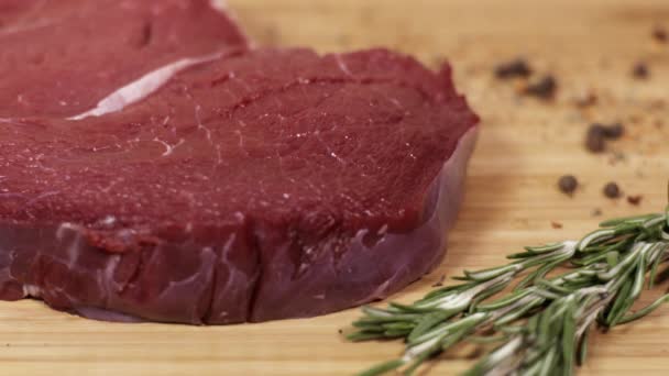 Bit av raw rött kött på bordet med rosmarin och kryddor — Stockvideo