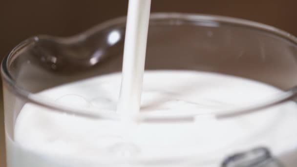 Verse melk giet in glazen pot in tekenreeks, spatten maken — Stockvideo