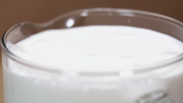 Чистое молоко в стеклянной банке в струнах, делая брызги — стоковое видео
