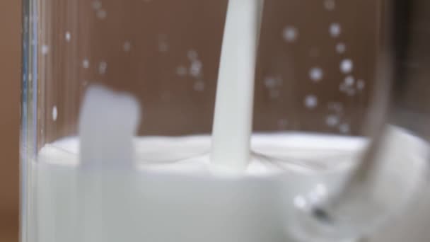La leche fresca se vierte en el frasco de vidrio en el pico, haciendo salpicaduras — Vídeos de Stock