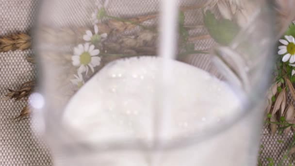 Le lait pur se déverse dans une cruche en verre en ficelle, faisant des éclaboussures — Video