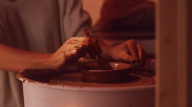 Kamera beyaz bluz kadında karanlık Studio potters tekerlek üzerinde çalışıyor gösterir.