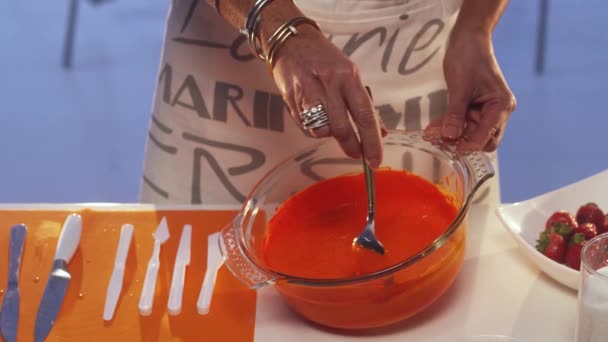 Femme main est agitant bouillie orange avec cuillère dans une grande casserole en verre sur la table — Video