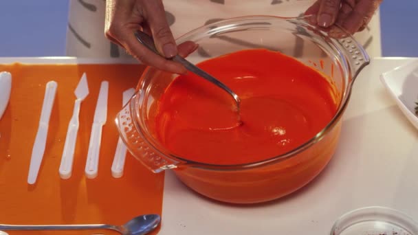 Orange ämne droppande från en sked i stora glas pan med breda kanter. — Stockvideo