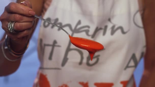Slow motion of orange substance spilling over metallic spoon and dripping down. — Stock Video