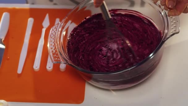 Fouet à la main de substance violette et blanche dans une grande casserole en verre ronde — Video