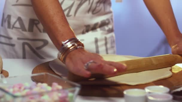 Vrouw in schort uitrolt deeg op ronde gevormde houten plank met deegroller — Stockvideo