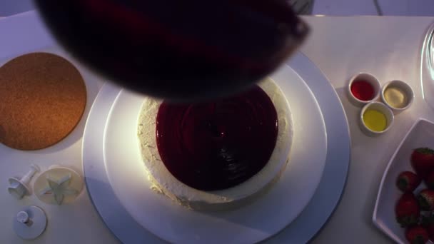 Dames hand draait gerechten met witte cake en giet violet crème op. — Stockvideo