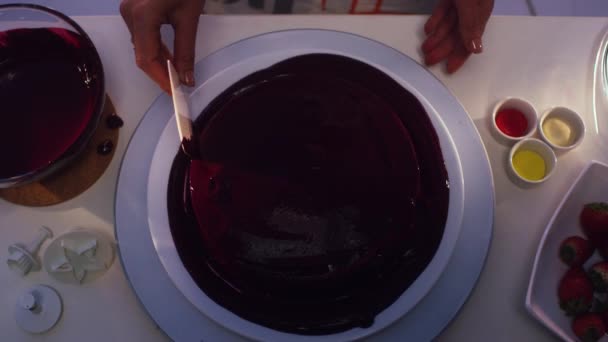 Bolo em forma redonda coberto com creme violeta está sendo alisado manualmente — Vídeo de Stock