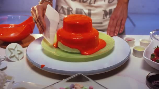 Petit gâteau double étage recouvert de crème orange est lentement lissé — Video