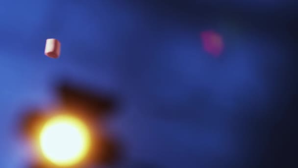 Много летящих цветных бочек в форме зефира на размытом темно-синем фоне — стоковое видео