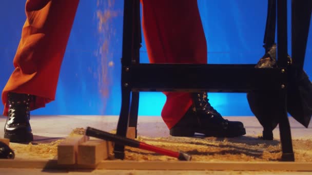 Πριονίδι καλύπτει ξύλινο πάτωμα με επανδρώνει πόδια σε πορτοκαλί παντελόνι και μαύρες μπότες — Αρχείο Βίντεο