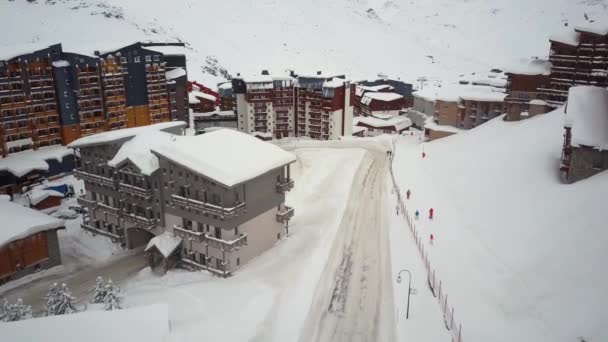 Drone camera ukazuje moderní, malý, zasněžené lyžařské městečko obklopené kopci — Stock video