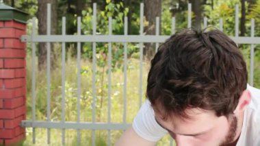 Genç adam t-shirt alır alyans dışarı-in gün ışığında ahşap çit arka plan üzerinde küçük mavi kadife kutu dışarı sakallı.