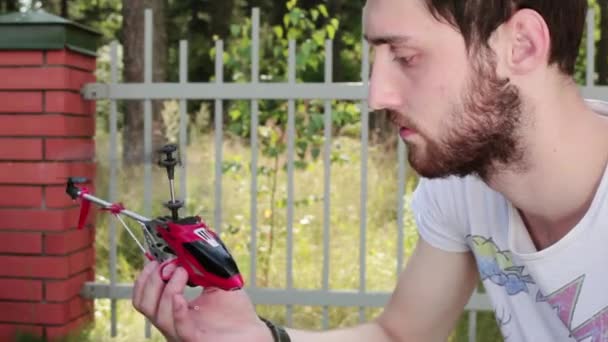 Dans la lumière du jour l'homme tient dans les mains allumé nano hélicoptère puis l'éteint . — Video