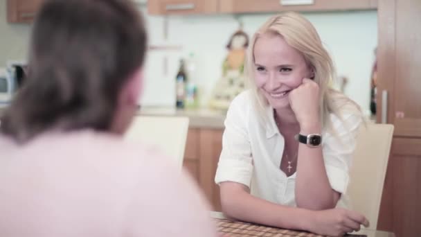 Carino ragazza bionda e giovane uomo vestito di bianco sono seduti a tavola in cucina — Video Stock