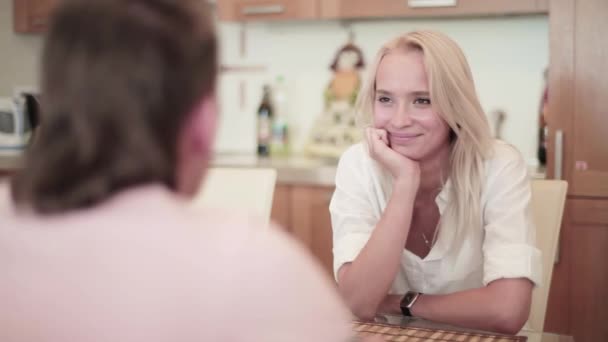 Pareja de hombres y mujeres jóvenes sentados en la mesa y teniendo una agradable charla cálida — Vídeos de Stock