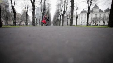 Adam kadife takım elbise ve kırmızı elbiseli kadın parkta kış sezonunda dans ediyor.