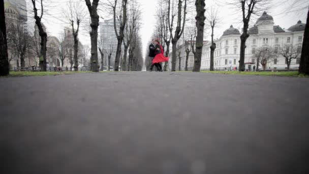 Hombre en traje de terciopelo y mujer en vestido rojo bailan tango en parque de otoño vacío . — Vídeos de Stock