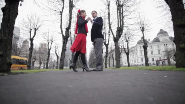 Man and woman dance tango in empty winter street surrounded by naked trees — Stock Video