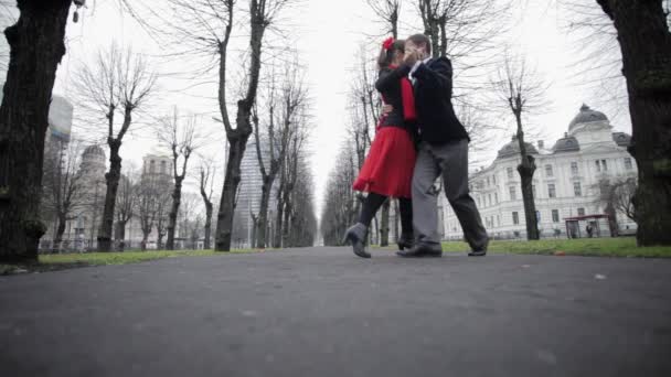 Joven lindo chico y chica son emocionalmente bailando en el parque entre los árboles desnudos — Vídeos de Stock
