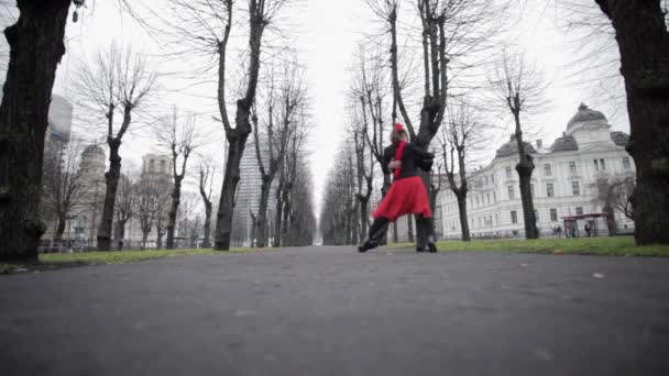 Hombre maduro en chaqueta de terciopelo danza con mujer en falda roja y bufanda en la calle . — Vídeos de Stock