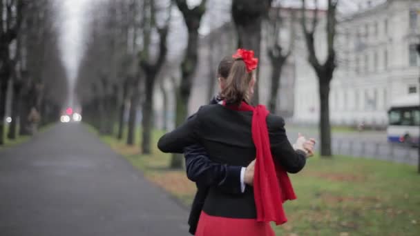 Barbudo lindo chico y bonita chica con bufanda roja están bailando en la calle de invierno — Vídeos de Stock