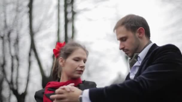 Aranyos ember kabát és csinos nő szoknyát és sálat végre meztelen fák között. — Stock videók