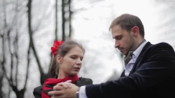 Veste homme mignon et jolie femme en jupe et écharpe effectuer parmi les arbres nus . — Video