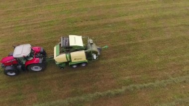 Viborg, Rusya Federasyonu - 11 Haziran 2018: Kamera büyük kırmızı traktör ekli çalışma sarı saman balya ile sahada gösterir.