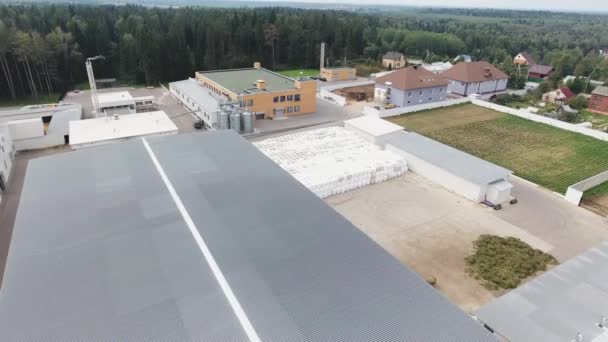 Drone flies over roofs of modern clean fenced farm with pile of round bales. — Stock Video