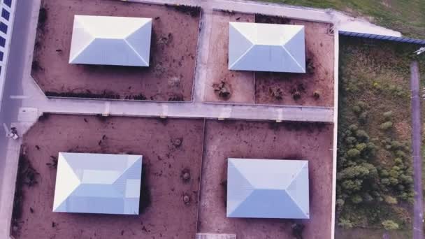 Drone camera catches roofs of modern fenced farm with square animal corral. — Stock Video