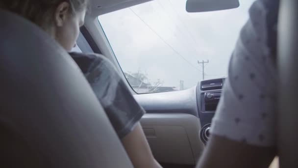 Мужчина и женщина сидят в машине и едут где-то в сельской местности в пасмурный день — стоковое видео