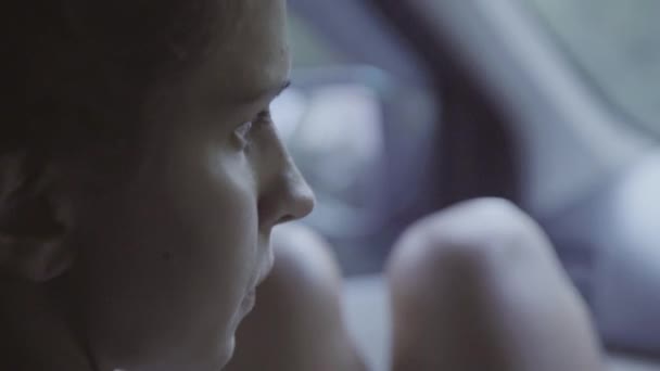 Retrato de mujer joven de ojos marrones con las rodillas desnudas sentado en el coche en movimiento — Vídeos de Stock