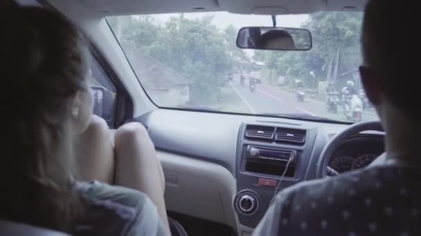 Junge kaukasische Kerle und Mädchen sitzen im Auto und fahren im ländlichen östlichen tropischen Raum. — Stockvideo