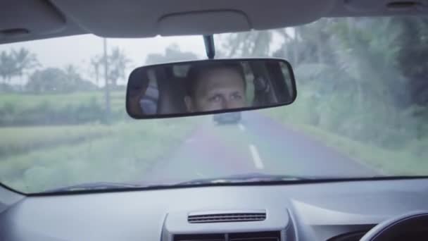 Ansikte av mogen kaukasiska man återspeglas på backspegeln i rörliga bil. — Stockvideo