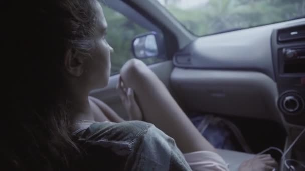 Vista lateral da jovem mulher de olhos castanhos com joelhos nus sentados em carro em movimento — Vídeo de Stock