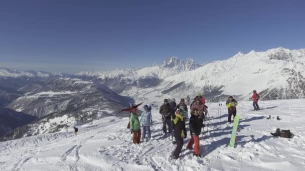 Grupo de esquiadores e snowboarders olhar para a câmera e acenar com as mãos no dia ensolarado — Vídeo de Stock