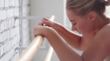 Sevimli sarışın kız bej tek parça streç giysi içinde barre bale sınıf egzersiz ısınmak