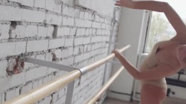 Tek parça streç giysi uygulamalarda çekici sarışın dans hareketleri üzerinde barre germe ile.