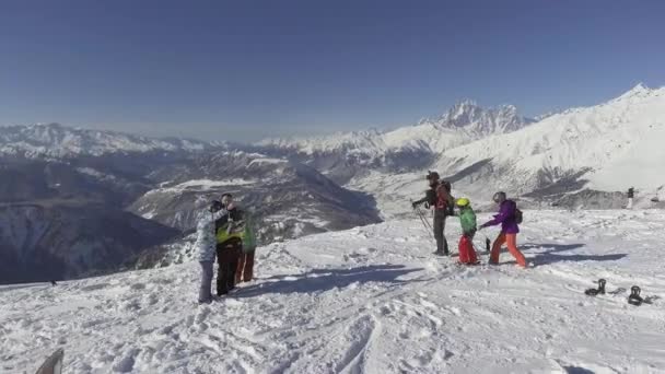 BAKURIANI, GEORGIA - 2 DE NOVIEMBRE DE 2017: Drone vuela círculos sobre esquiadores y snowboarders en la cima de la colina cubierta de nieve de invierno — Vídeos de Stock