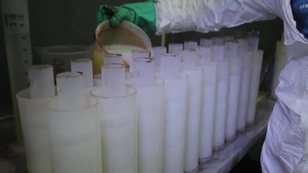 Rijen met plastic waterfilters worden wordt gevuld met witte vloeistof door werknemer. — Stockvideo