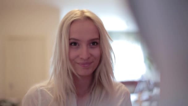 Jolie fille blonde souriante se tient à la porte ouverte, regarde l'homme qui l'embrasse 