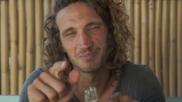 Cute Guy With Long Curly Hair Holds Bottle Looks At Camera Speaks And Smiles