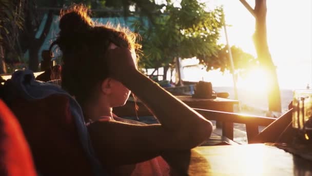 Retrato de una hermosa joven sentada en chaise-longue y mirando el atardecer — Vídeos de Stock