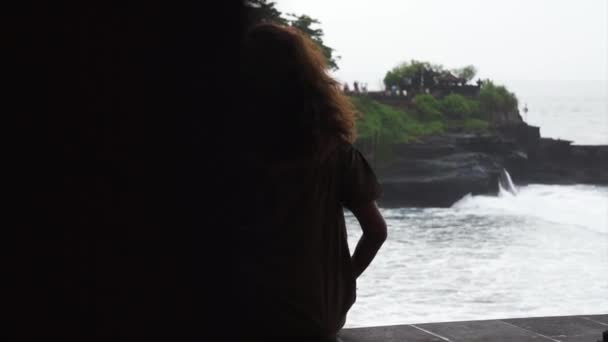 Mulher com cabelo encaracolado levando vídeo da costa do mar por pequena câmera com monopod — Vídeo de Stock