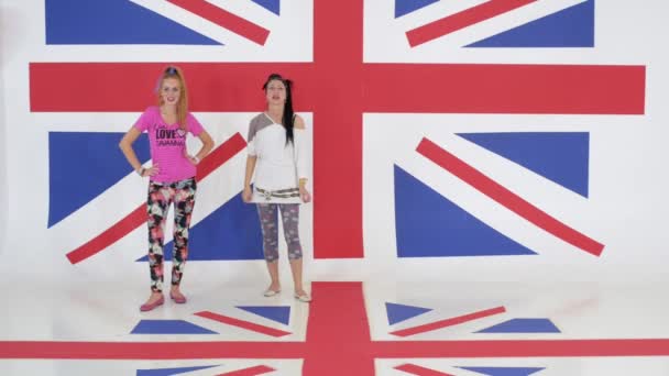Probe von zwei charmanten Mädchen, die auf dem Hintergrund der britischen Flagge tanzen — Stockvideo