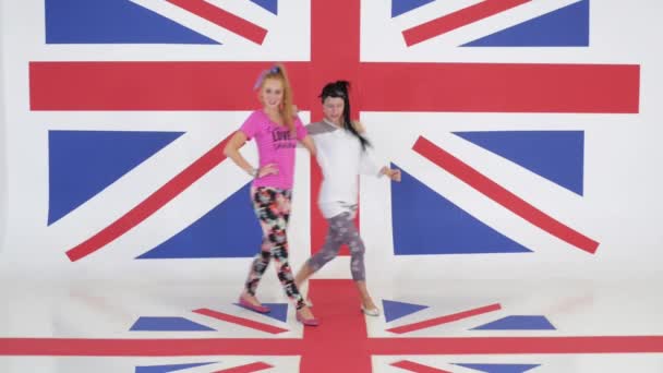 Ensayo de dos chicas divertidas lindas bailando sobre el fondo de la textura de la bandera del Reino Unido . — Vídeos de Stock